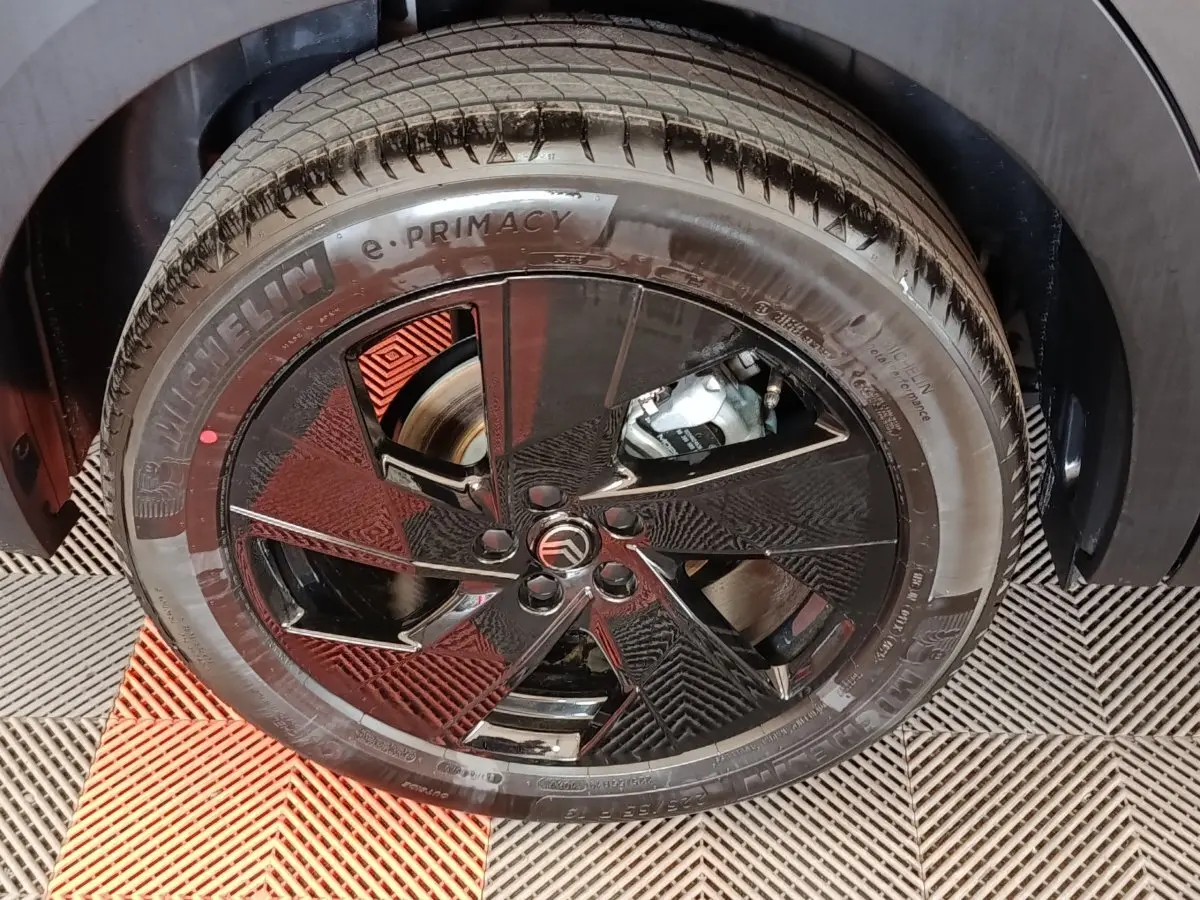 Gros plan sur la roue avant droite avec jante noire brillante et logo Citroën au centre, pneu Michelin e-Primacy.