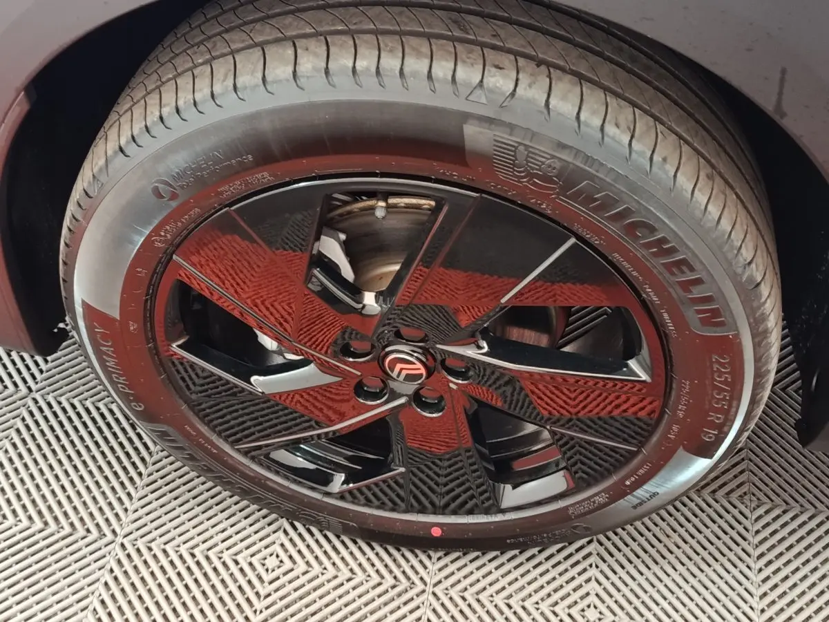 Gros plan sur la roue avant droite du Citroën C5 Hybride gris foncé avec jante noire brillante et logo Citroën central.
