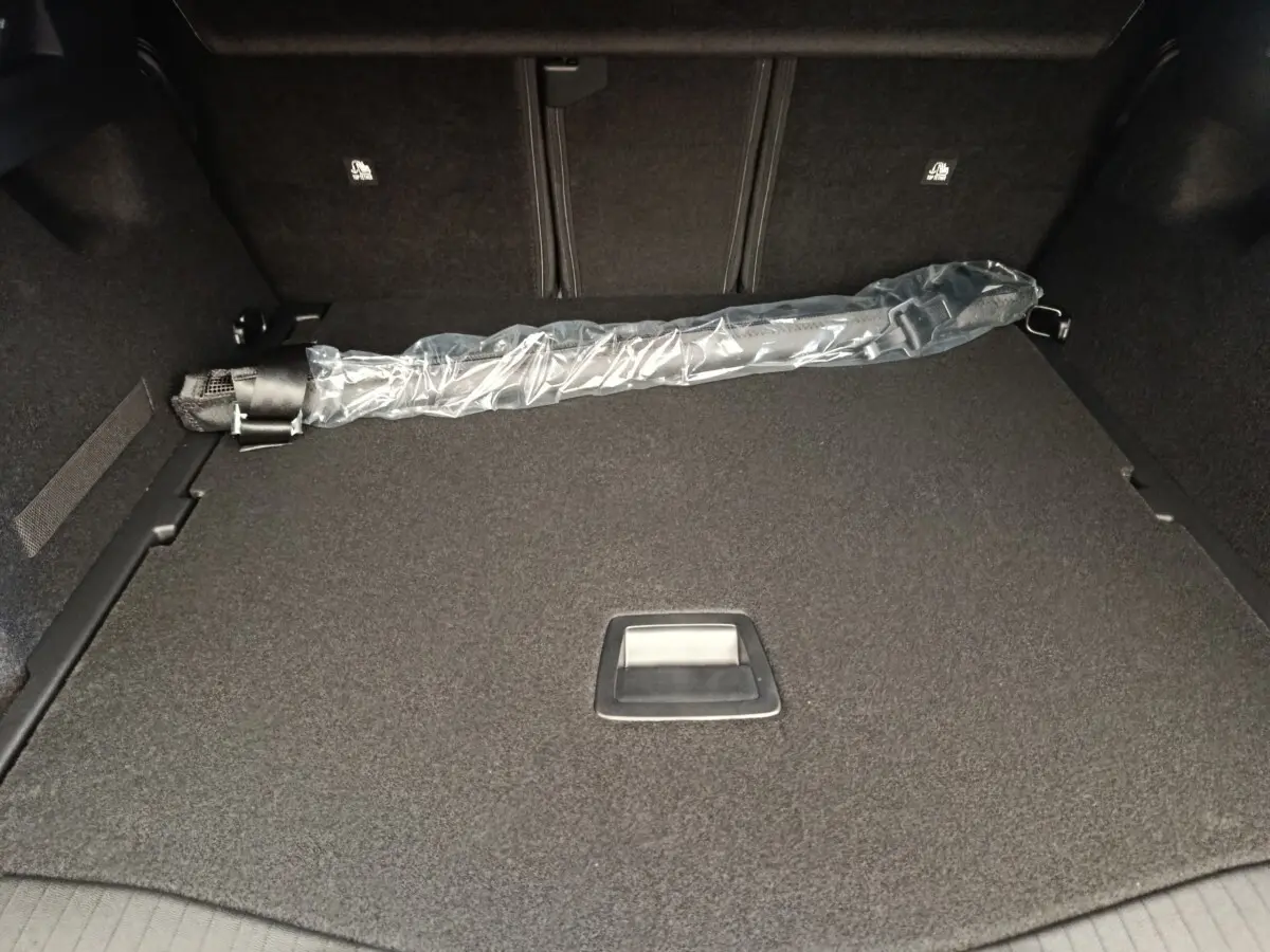 Coffre spacieux de Citroën C5 Hybride gris foncé vu de l’intérieur, avec protection et rangement intégré.