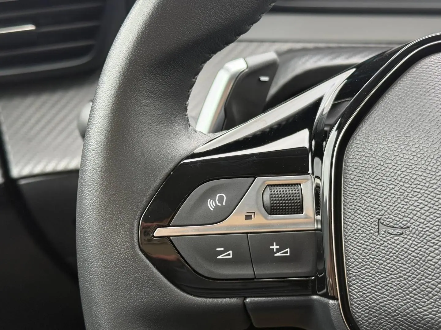Gros plan sur les commandes audio au volant noir brillant du Peugeot 208 1.2 Hybrid 110ch Style 2025.