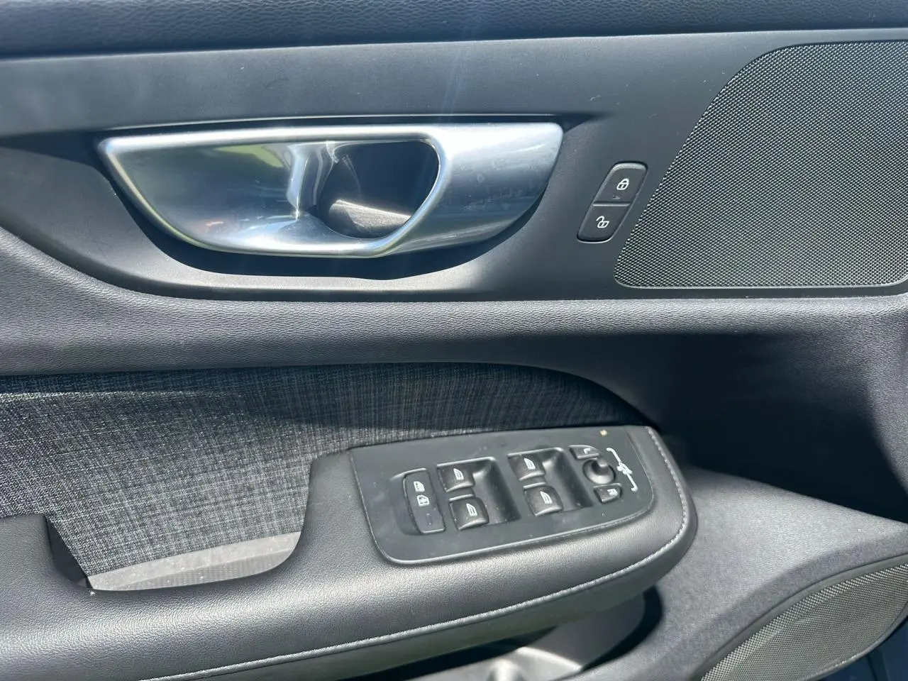 Poignée de porte intérieure côté gauche de Volvo S60 2024 en Thunder Grey avec commandes de vitres et verrouillage.