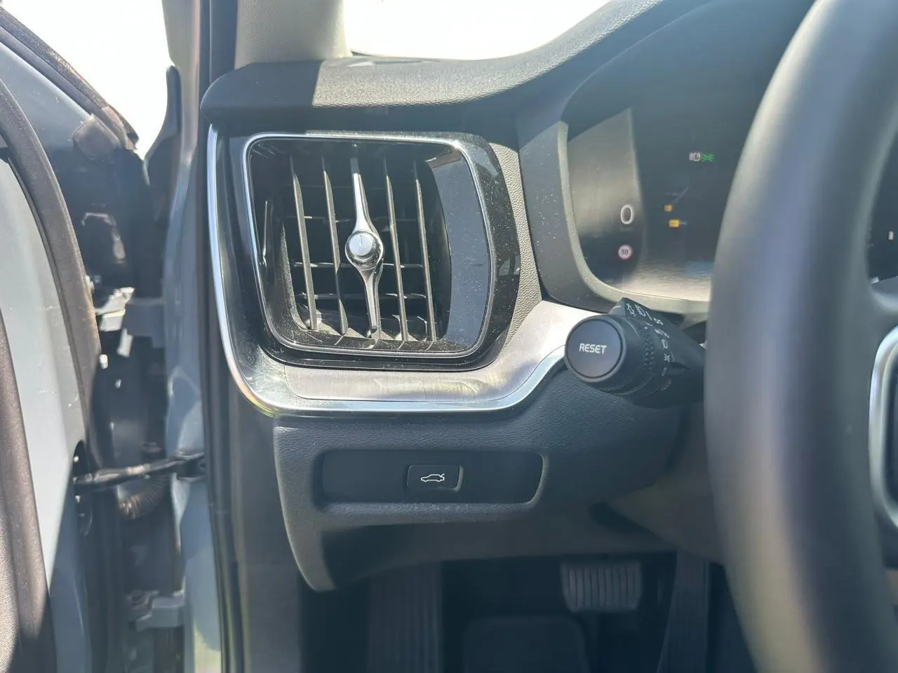 Détail de l'aération et bouton d'ouverture du coffre côté gauche du tableau de bord d'une Volvo S60 Thunder Grey 2024