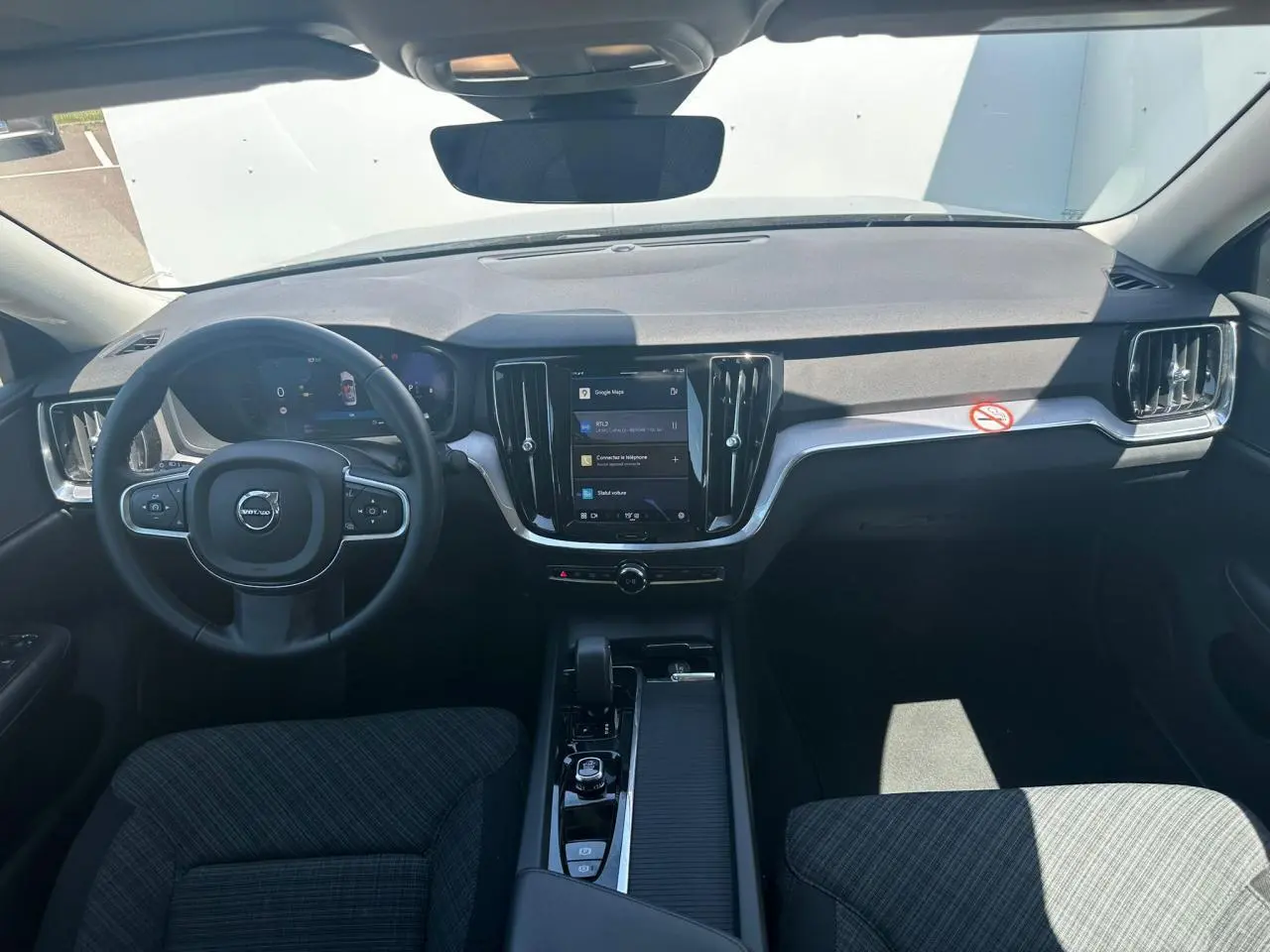 Vue intérieure avant du tableau de bord et volant noir de la Volvo S60 2024 avec écran tactile central vertical.
