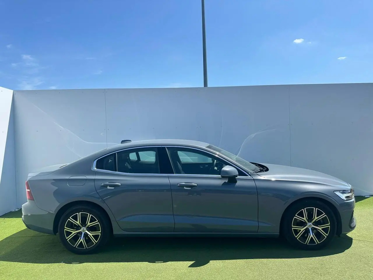 Profil côté gauche d'une Volvo S60 2024 Thunder Grey Metal avec jantes alliage 17 pouces en Y noir et diamant.