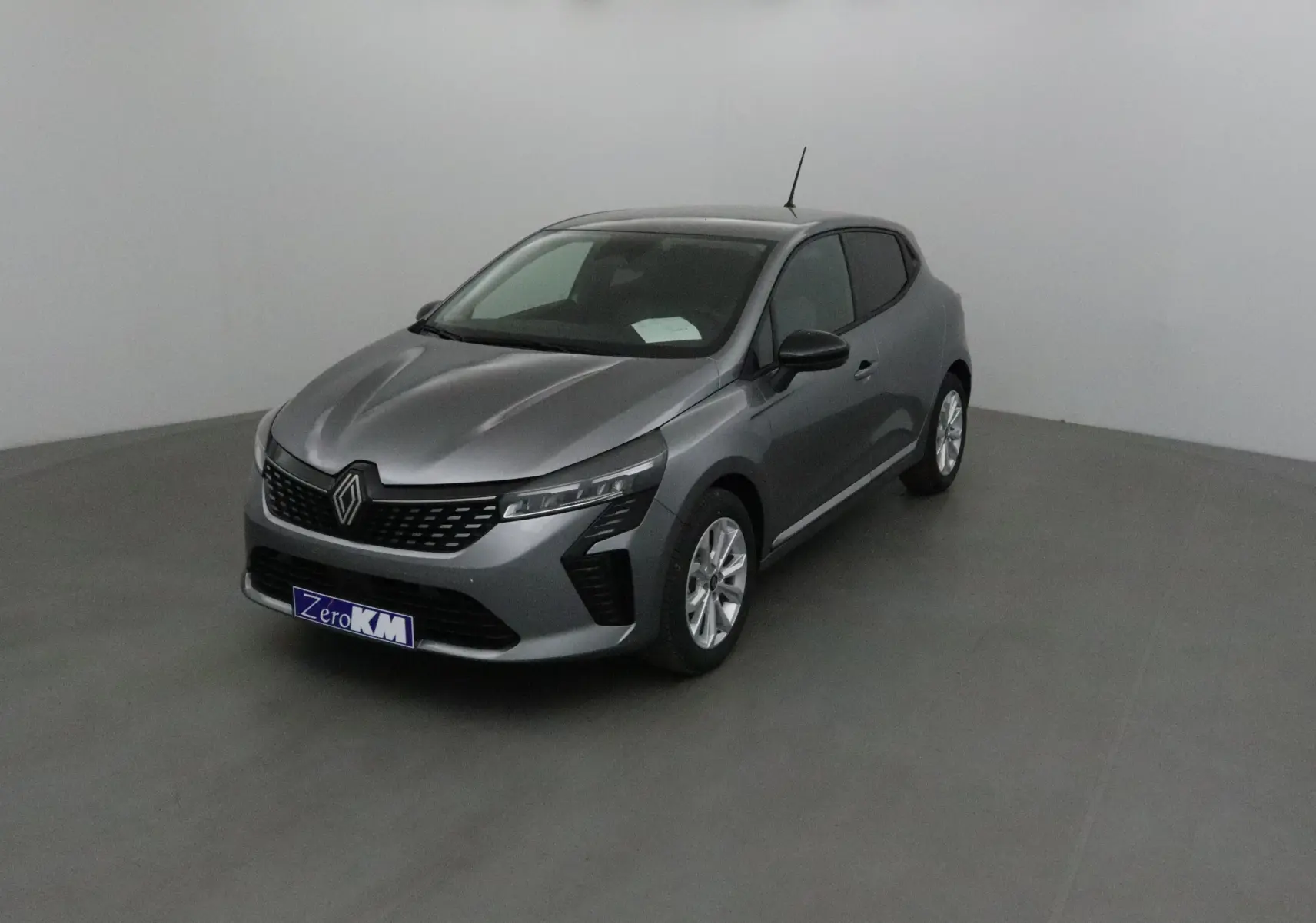 Renault Clio V gris schiste en 3/4 avant droit, avec protections latérales chromées et jantes alliage 16 pouces.