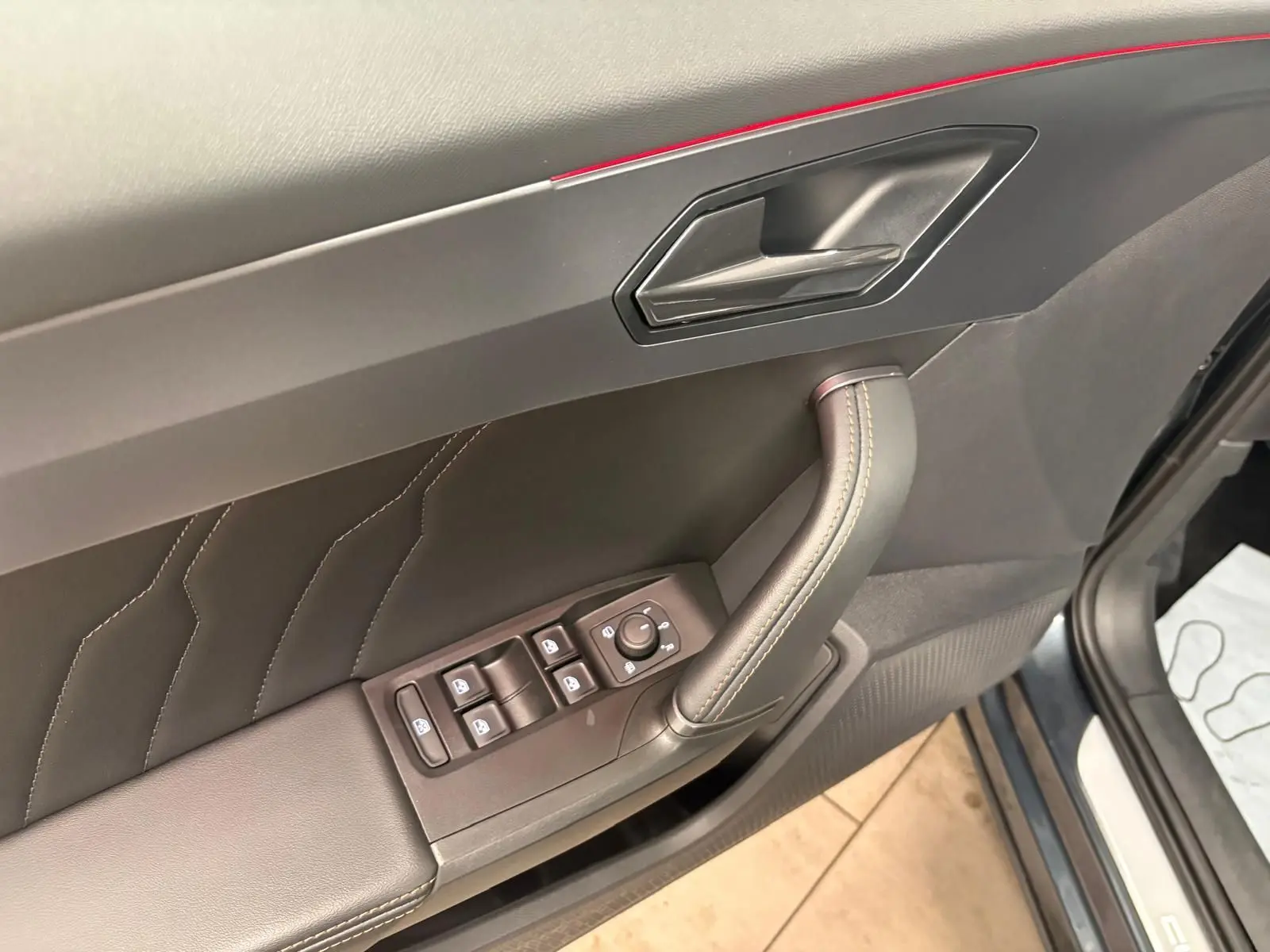 Gros plan sur la porte avant gauche de la CUPRA Formentor gris magnétique, montrant les commandes des vitres et la poignée intérieure.