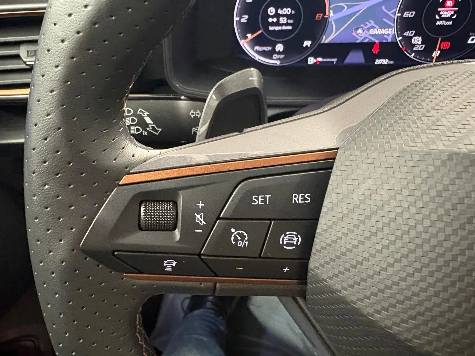 Gros plan sur les commandes à gauche du volant perforé du CUPRA Formentor gris magnétique, avec tableau de bord numérique en arrière-plan.