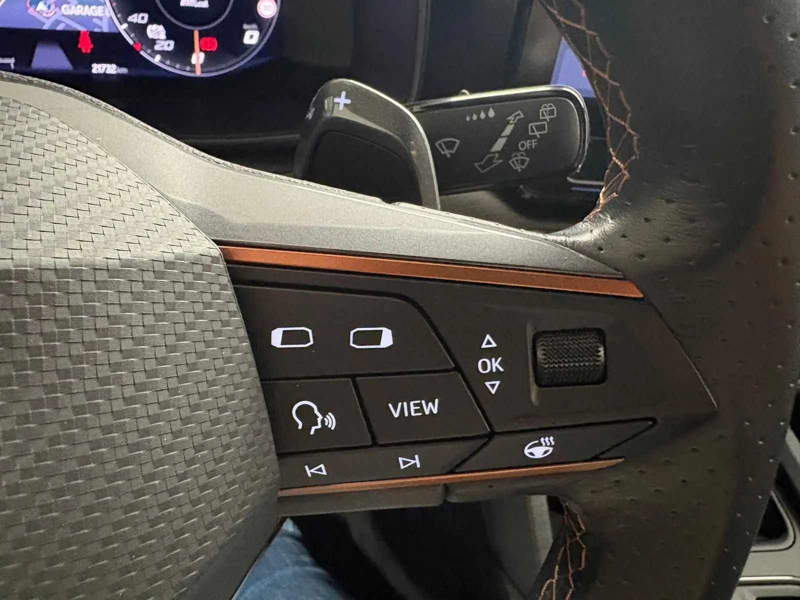 Gros plan sur les commandes du volant cuir perforé avec surpiqûres marron du CUPRA Formentor gris magnétique 2024.