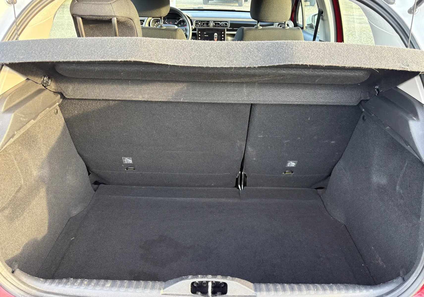 Vue du coffre ouvert d'une Citroën C3 rouge 2018, montrant l'espace de chargement et l'intérieur arrière du véhicule.