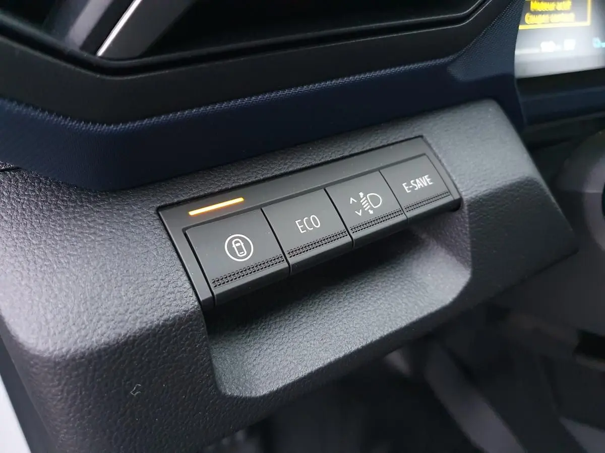 Gros plan sur les boutons de mode de conduite du tableau de bord du Dacia Duster 1.6 Hybrid blanc glacier.