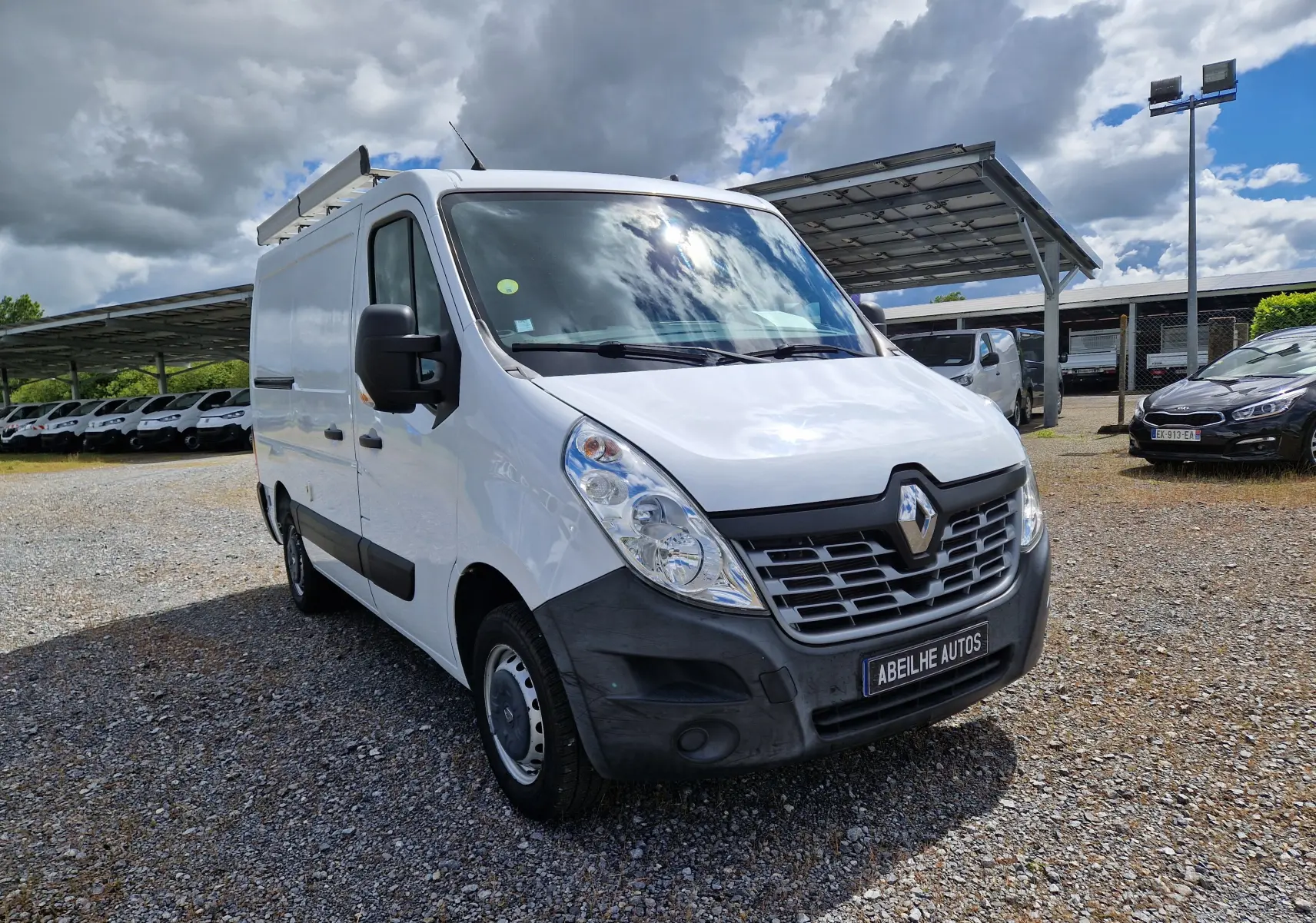 Renault Master blanc en vue 3/4 avant droit, fourgon utilitaire avec galerie de toit et pare-chocs noir.