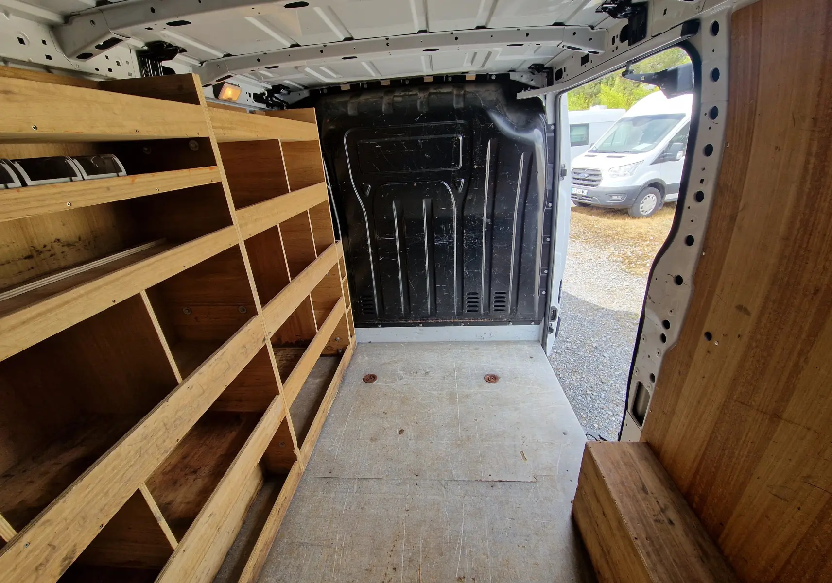 Vue intérieure arrière du Renault Master blanc 2019 avec aménagements bois et porte latérale ouverte.