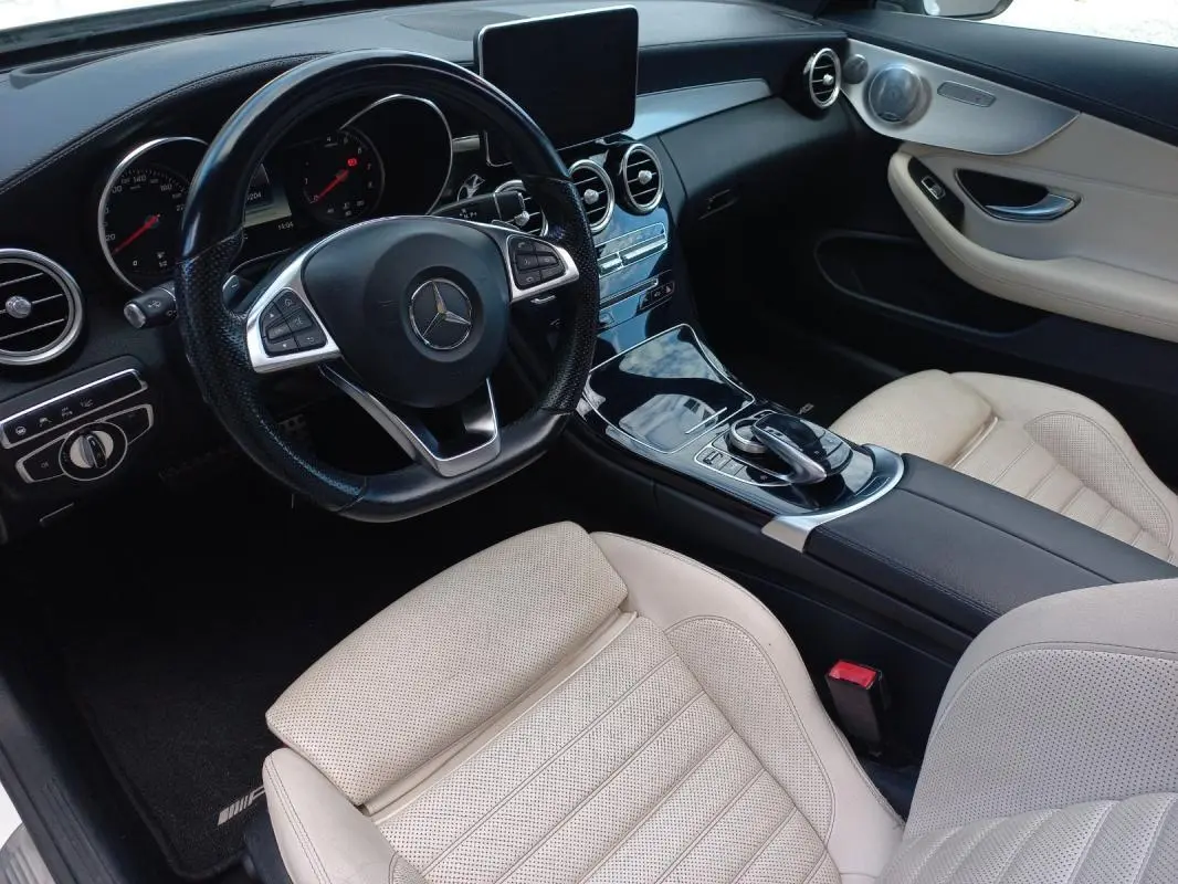 Vue intérieure côté conducteur de la Mercedes Classe C Coupé 2016, sièges cuir beige et tableau de bord noir brillant.