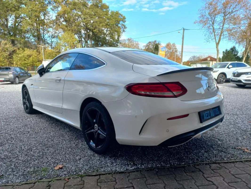 Mercedes Classe C Coupé blanc vue 3/4 arrière droit, jantes noires 18 pouces et toit ouvrant électrique visible.