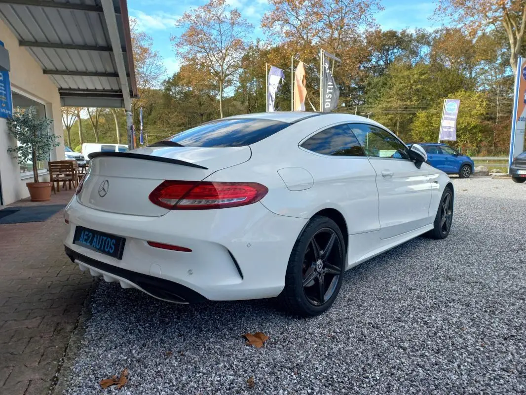 Mercedes Classe C Coupé blanc vue 3/4 arrière droit, avec jantes noires et toit ouvrant électrique visible.