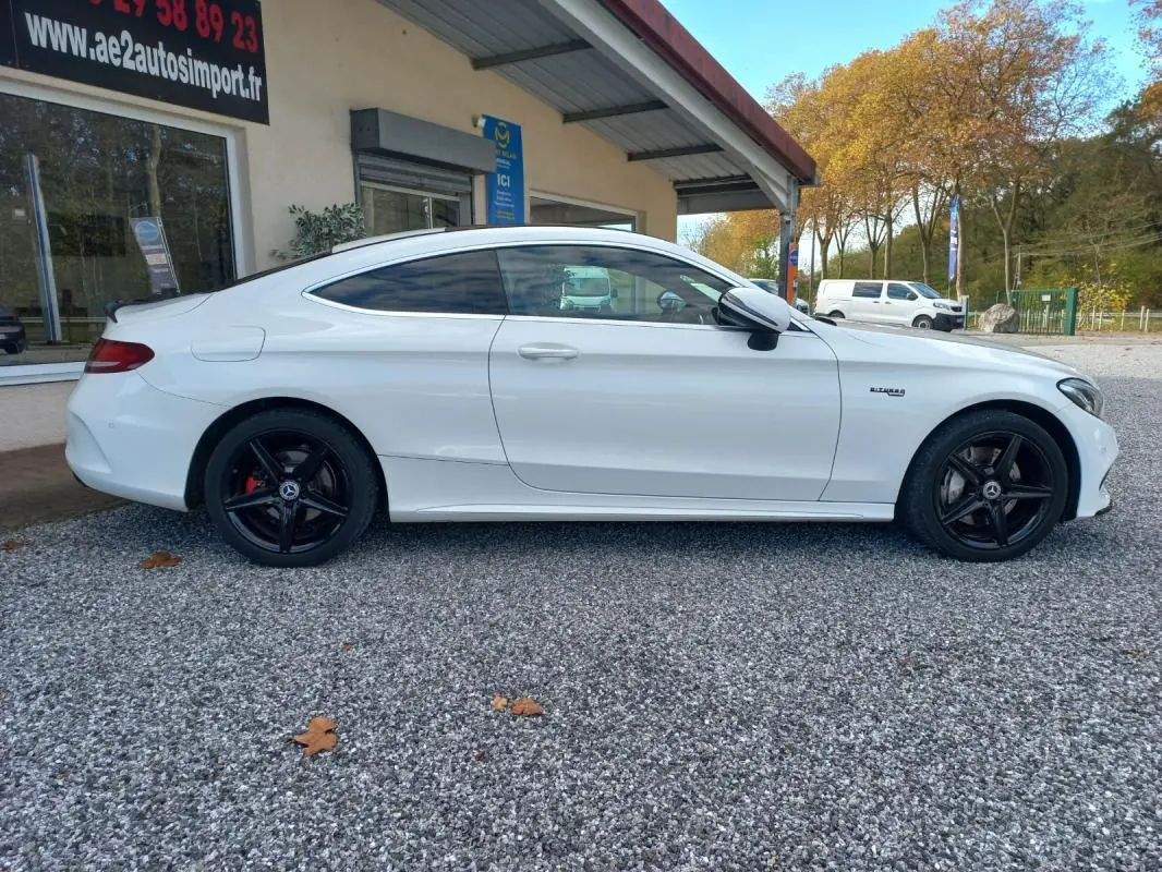 Vue de profil côté gauche d'une Mercedes Classe C Coupé blanc avec jantes noires et toit ouvrant électrique.
