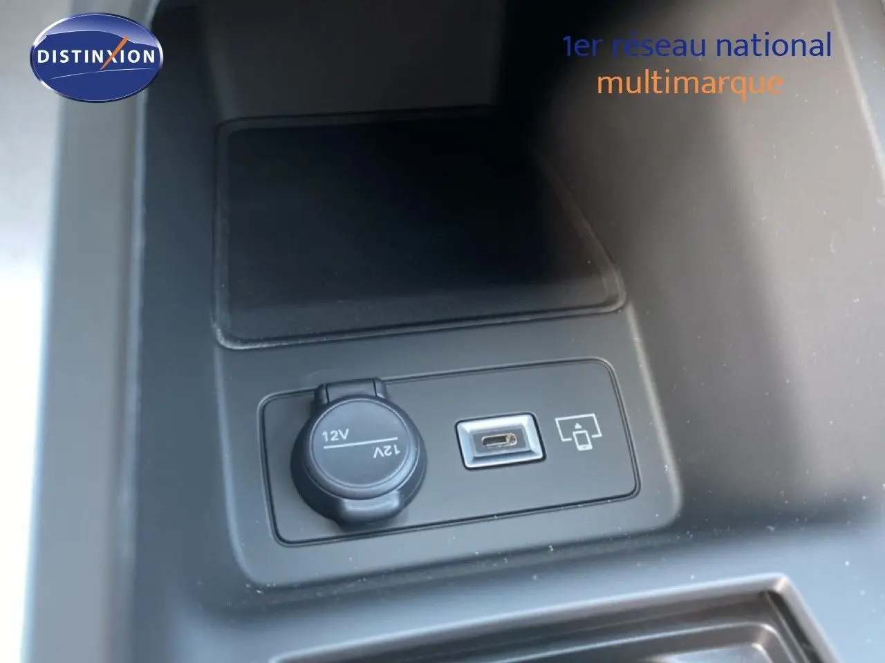 Prise 12V et port USB intégrés dans la console centrale d’une Peugeot 308 Hybrid blanche, vue intérieure rapprochée.