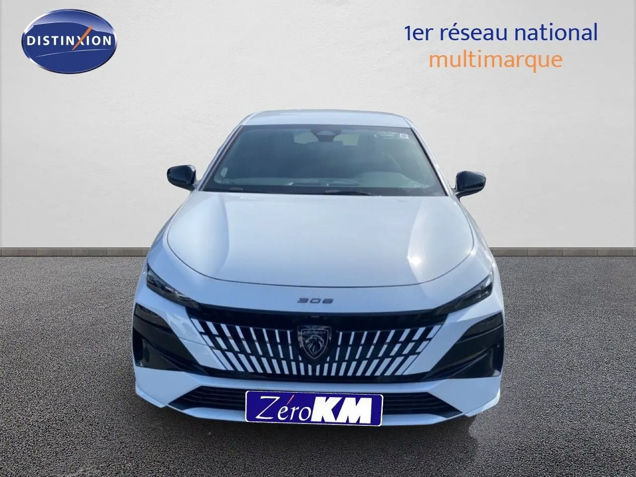 Vue de face d'une Peugeot 308 Hybrid 145ch GT blanche Okenite Metal avec calandre noire distinctive et logo lion central.