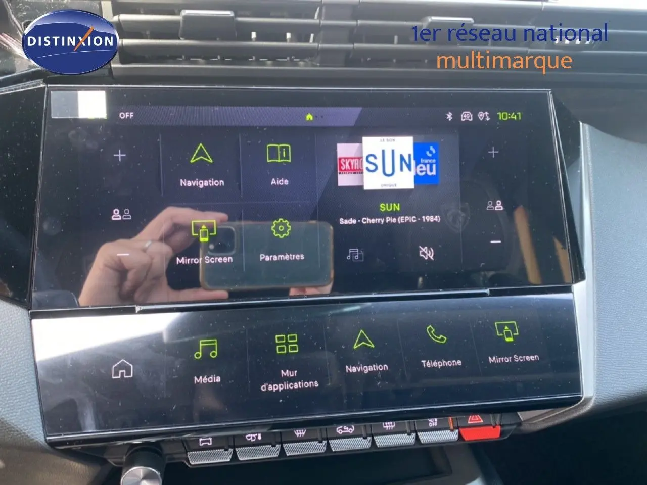 Vue rapprochée de l'écran tactile central de la Peugeot 308 Hybrid blanc Okenite, affichant le menu multimédia et navigation.