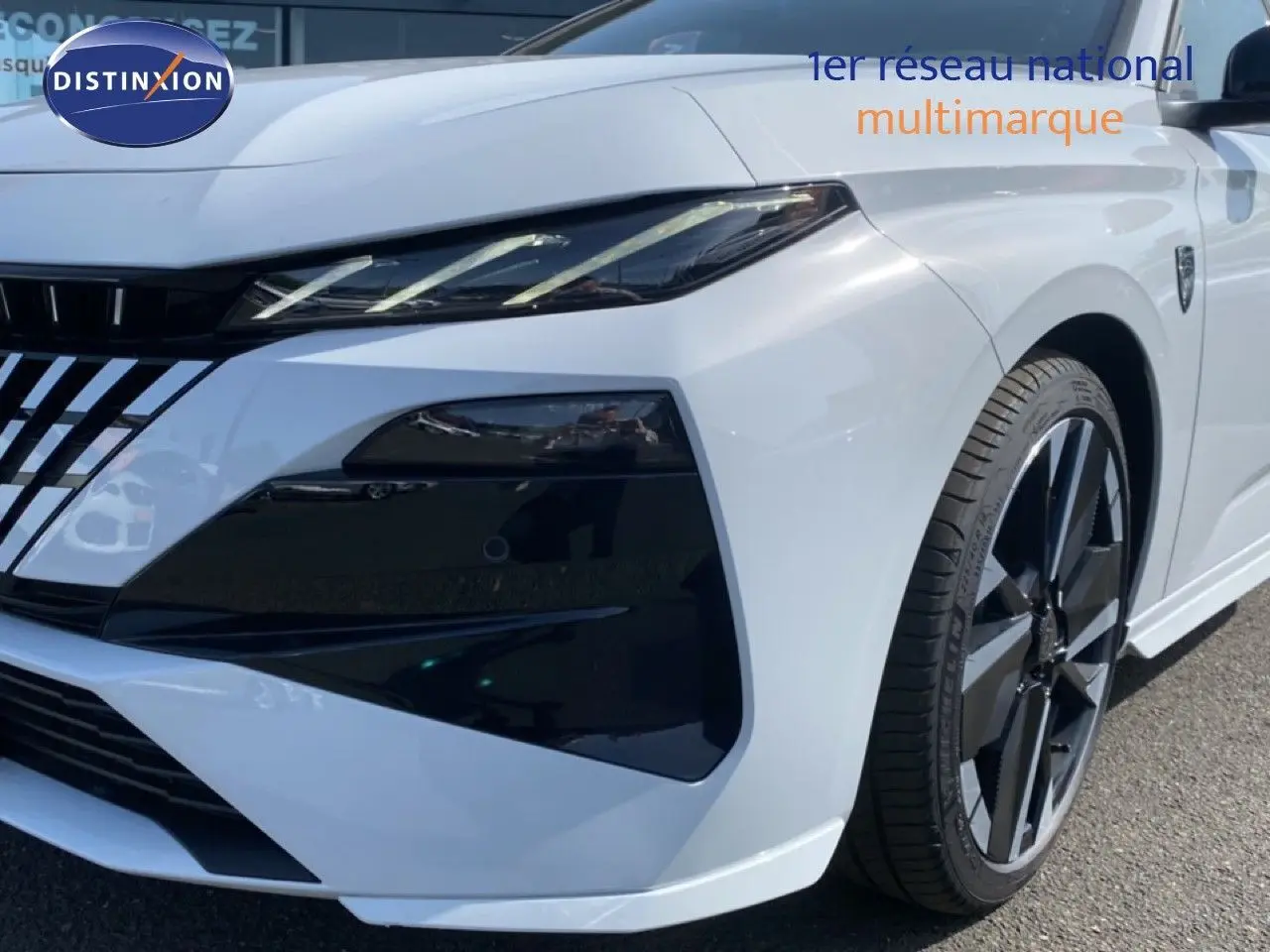 Vue 3/4 avant droit d'une Peugeot 308 Hybrid blanche Okenite Metal avec phares et jantes noires distinctives.