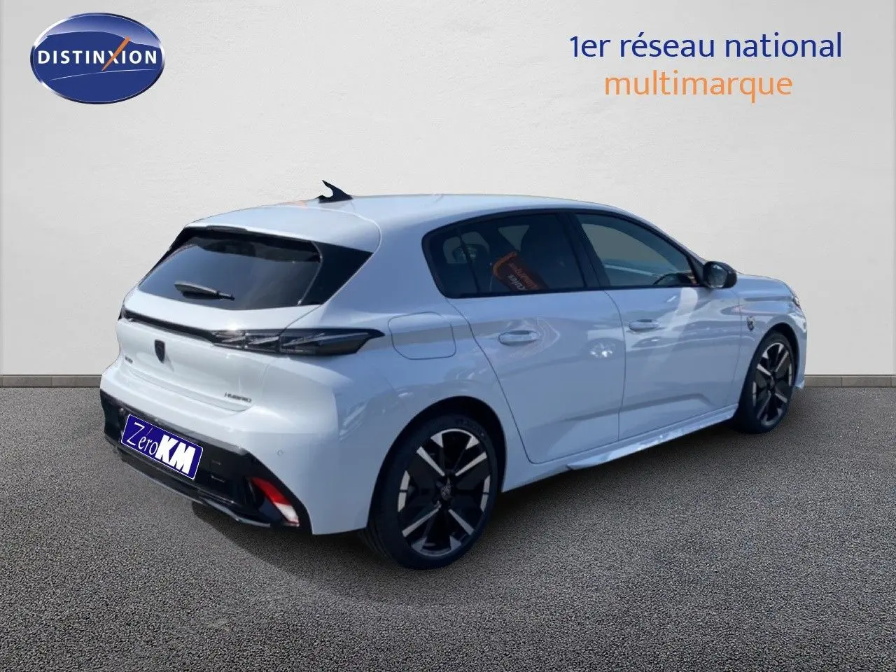 Vue 3/4 arrière droite d'une Peugeot 308 Hybrid 145ch GT blanche Okenite Metal avec jantes noires distinctives.