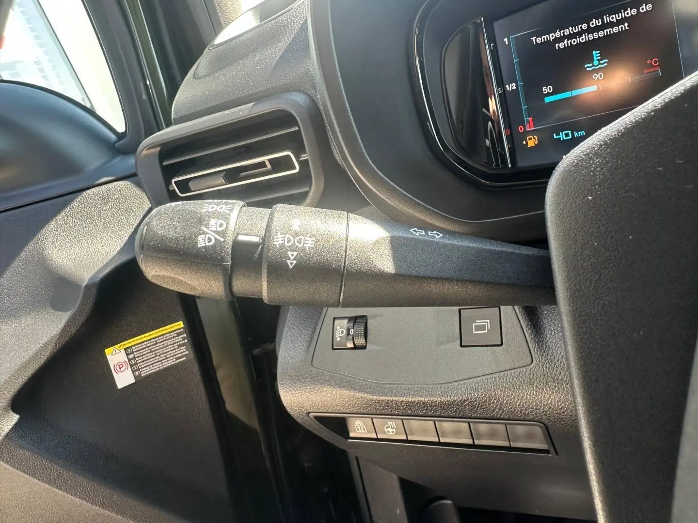 Gros plan sur la commande des feux à gauche du volant dans l’habitacle sombre du Citroën Berlingo 2026.