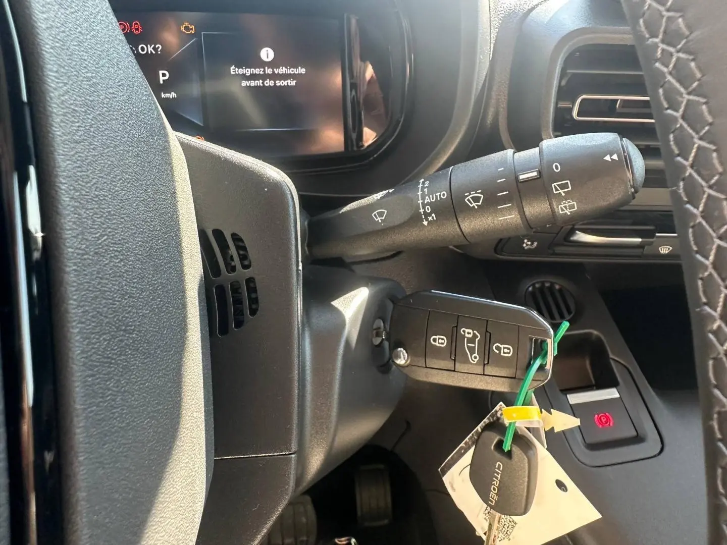 Vue rapprochée du tableau de bord et clé de contact du Citroën Berlingo 2026, avec affichage digital et volant partiel.