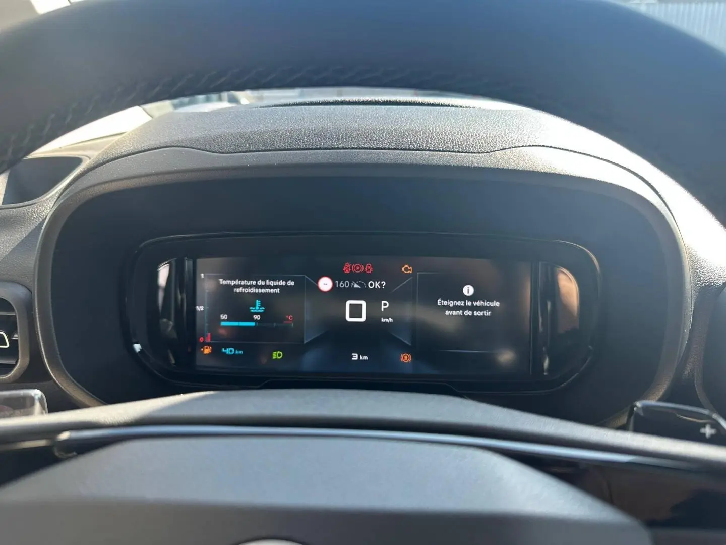 Vue rapprochée du tableau de bord numérique du Citroën Berlingo 2026, affichage des alertes et vitesse à zéro.