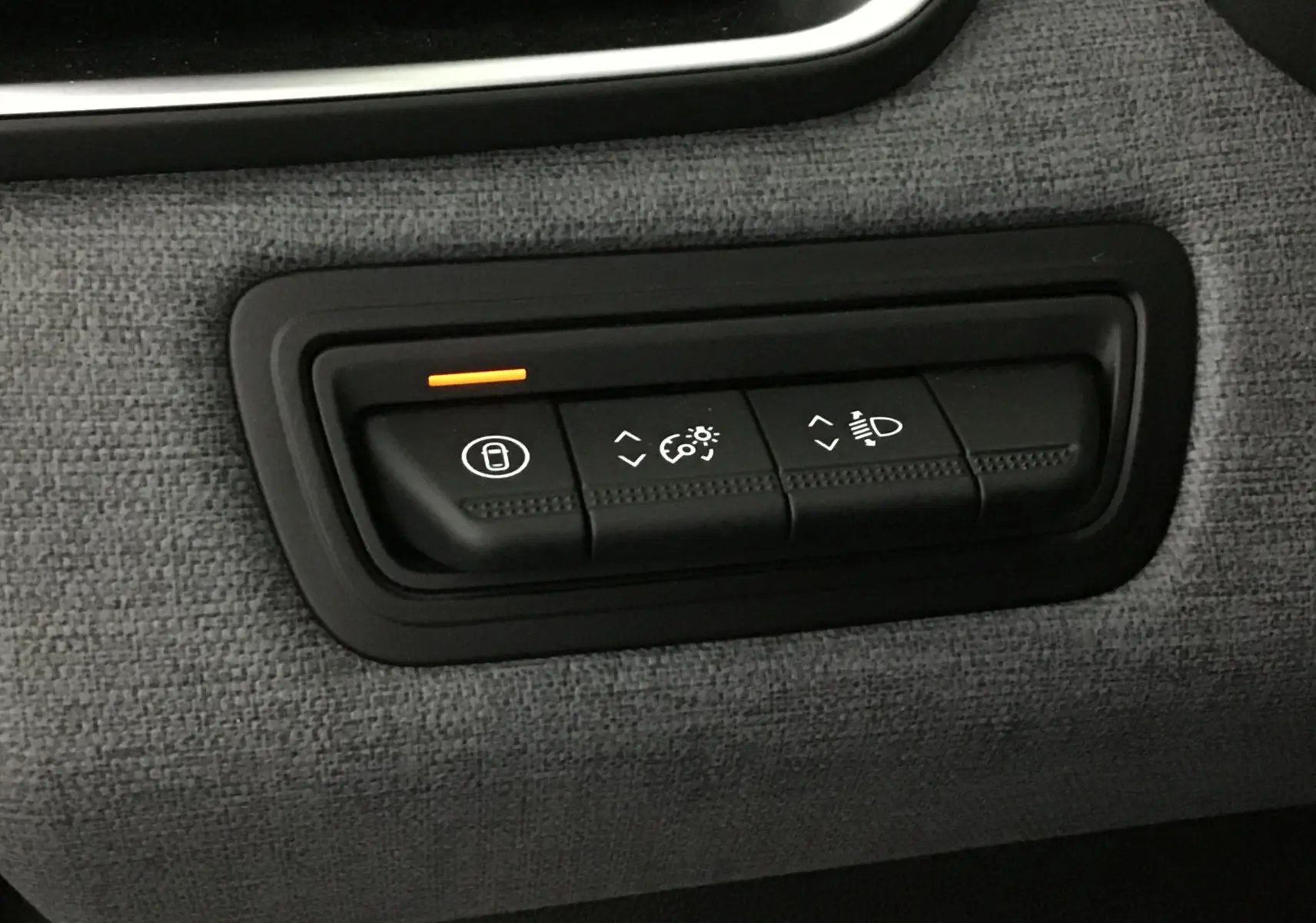 Panneau de commandes intérieures en tissu gris schiste de la Renault Clio V 2025, avec bouton de verrouillage éclairé en orange.