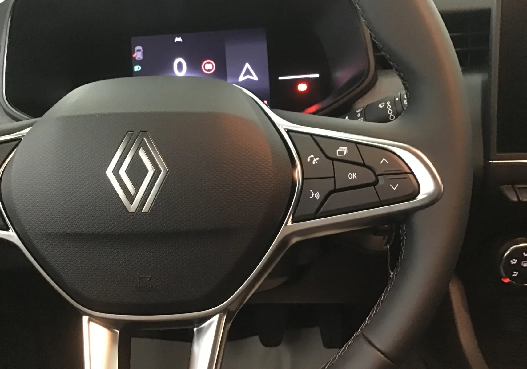 Gros plan sur le volant multifonction de la Renault Clio V 1.5 DCI 100 Evolution, avec commandes et logo central visible.