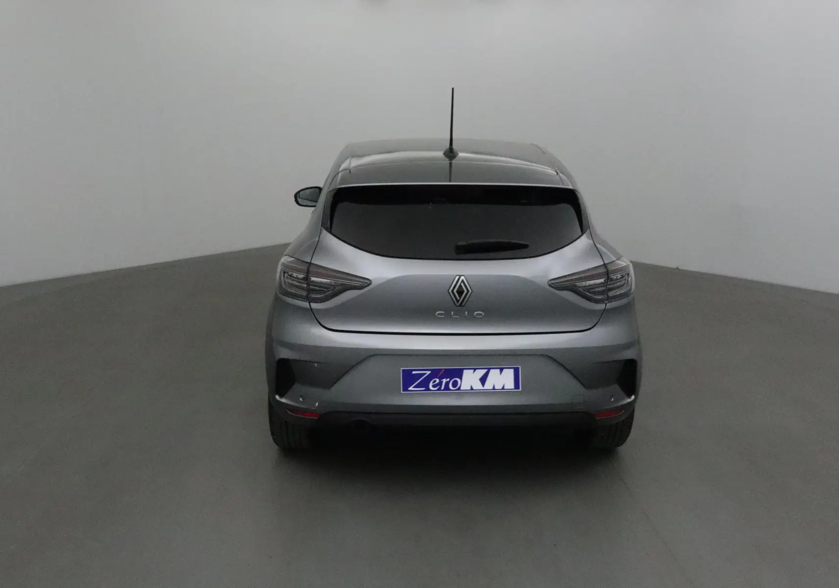Vue arrière d'une Renault Clio V gris schiste 2025 avec vitres teintées et logo distinctif au centre.
