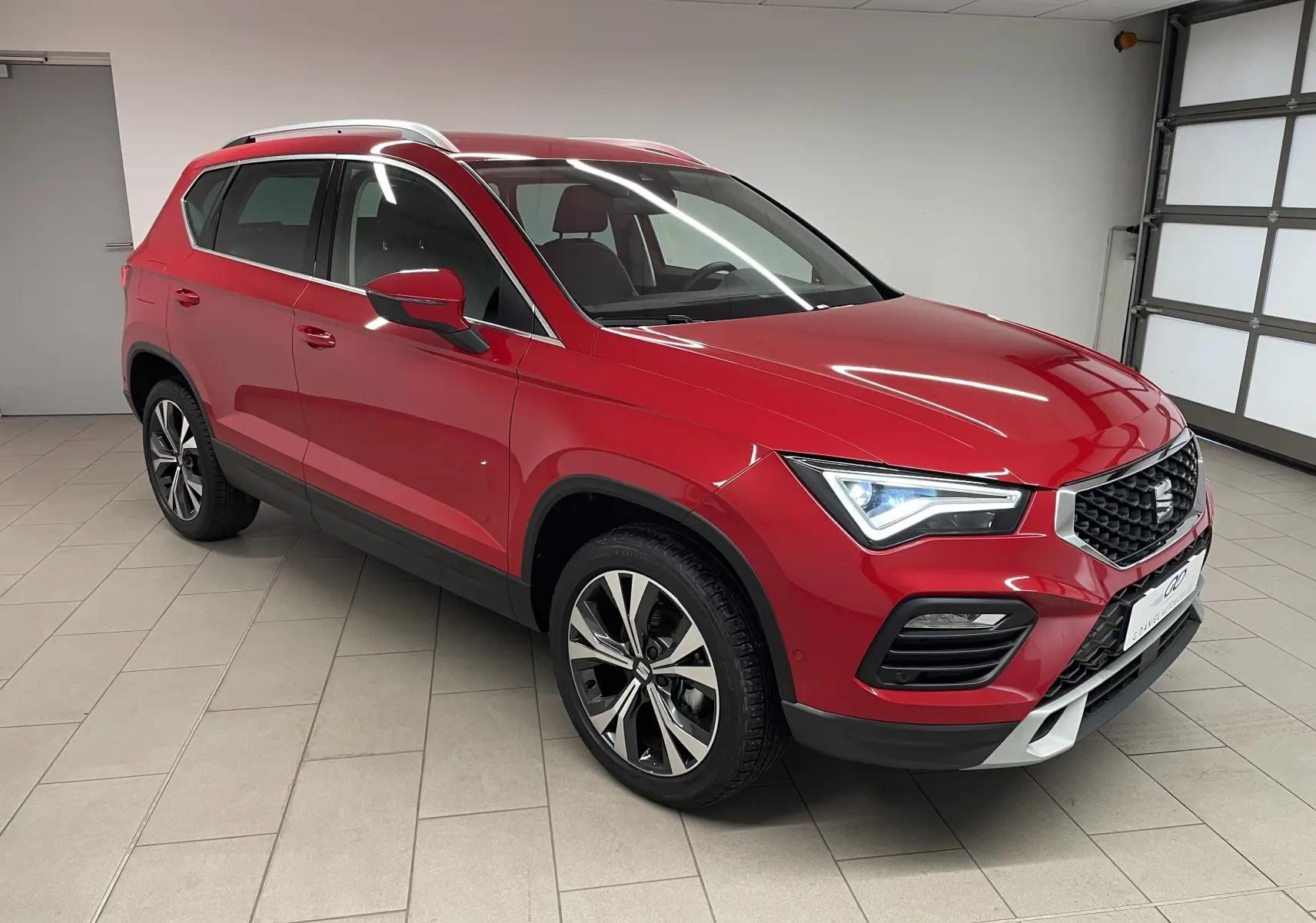 SEAT Ateca 2024 Rouge Velvet en 3/4 avant droit, avec jantes 18 pouces usinées et phares allumés.