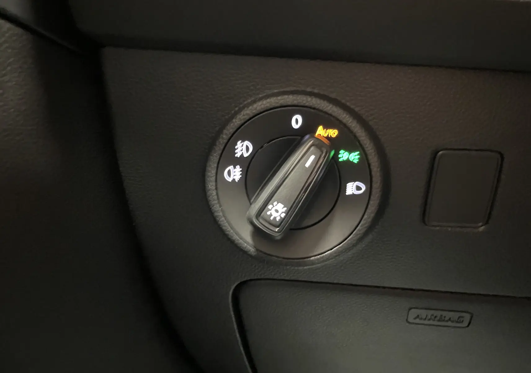 Commande des phares en mode automatique sur tableau de bord noir du SEAT Ateca Rouge Velvet 2024 côté gauche.