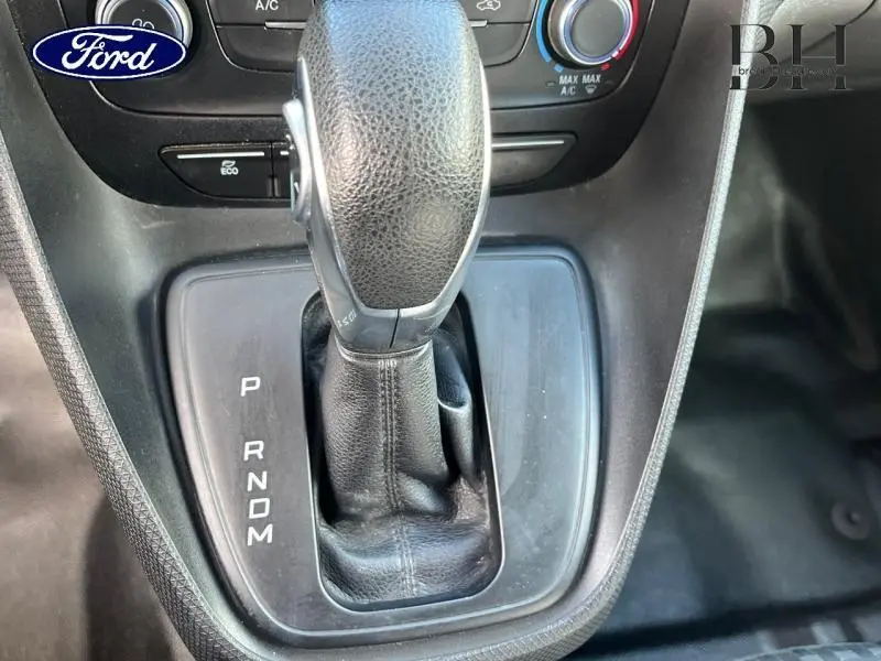 Gros plan sur le levier de vitesses automatique noir du Ford Transit Connect blanc glacier, avec commandes de climatisation en arrière-plan.