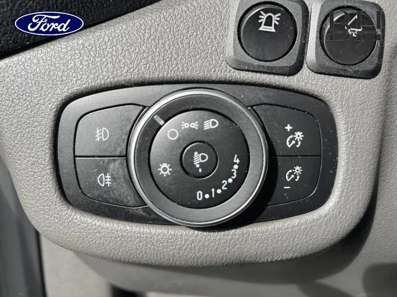 Gros plan sur le panneau de commande des phares du Ford Transit Connect blanc glacier, avec réglages d’éclairage et boutons auxiliaires.