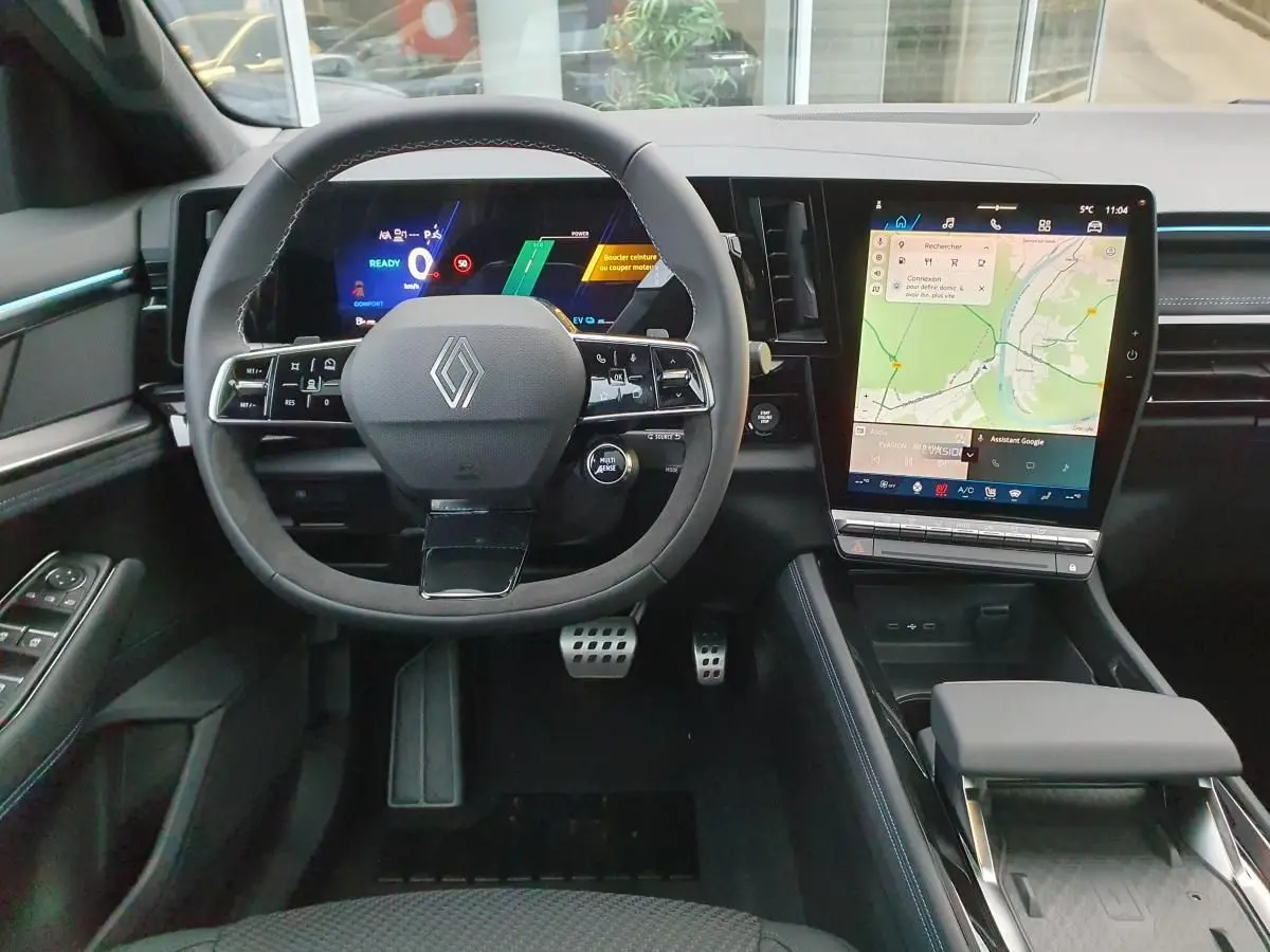 Vue intérieure avant du Renault Austral 2025, tableau de bord noir avec écran tactile vertical et volant Alcantara.