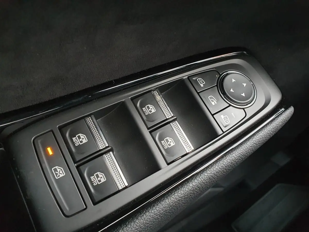 Gros plan sur les commandes de lève-vitres et rétroviseurs côté conducteur du Renault Austral gris schiste avec toit noir.