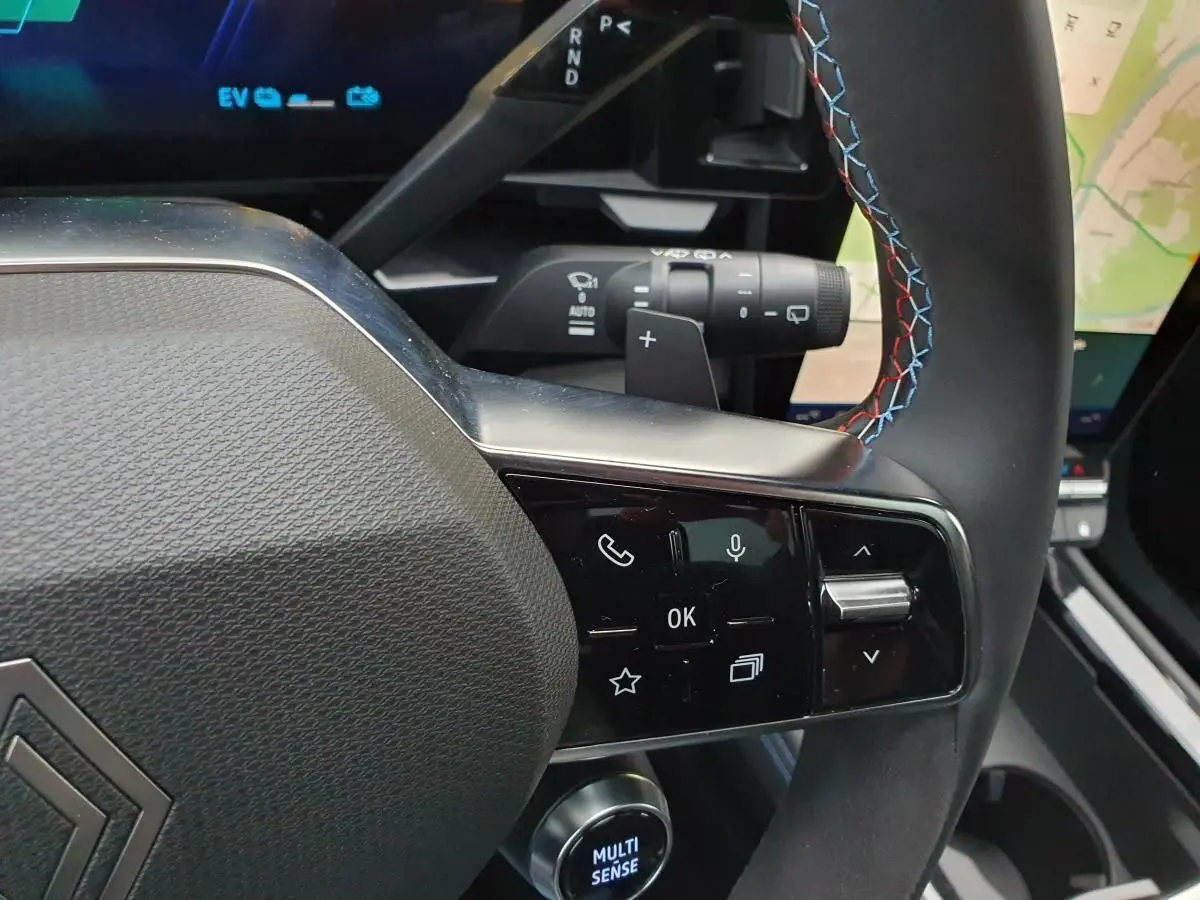 Gros plan sur le volant Alcantara avec surpiqûres tricolores et commandes multifonctions du Renault Austral hybride 2025.