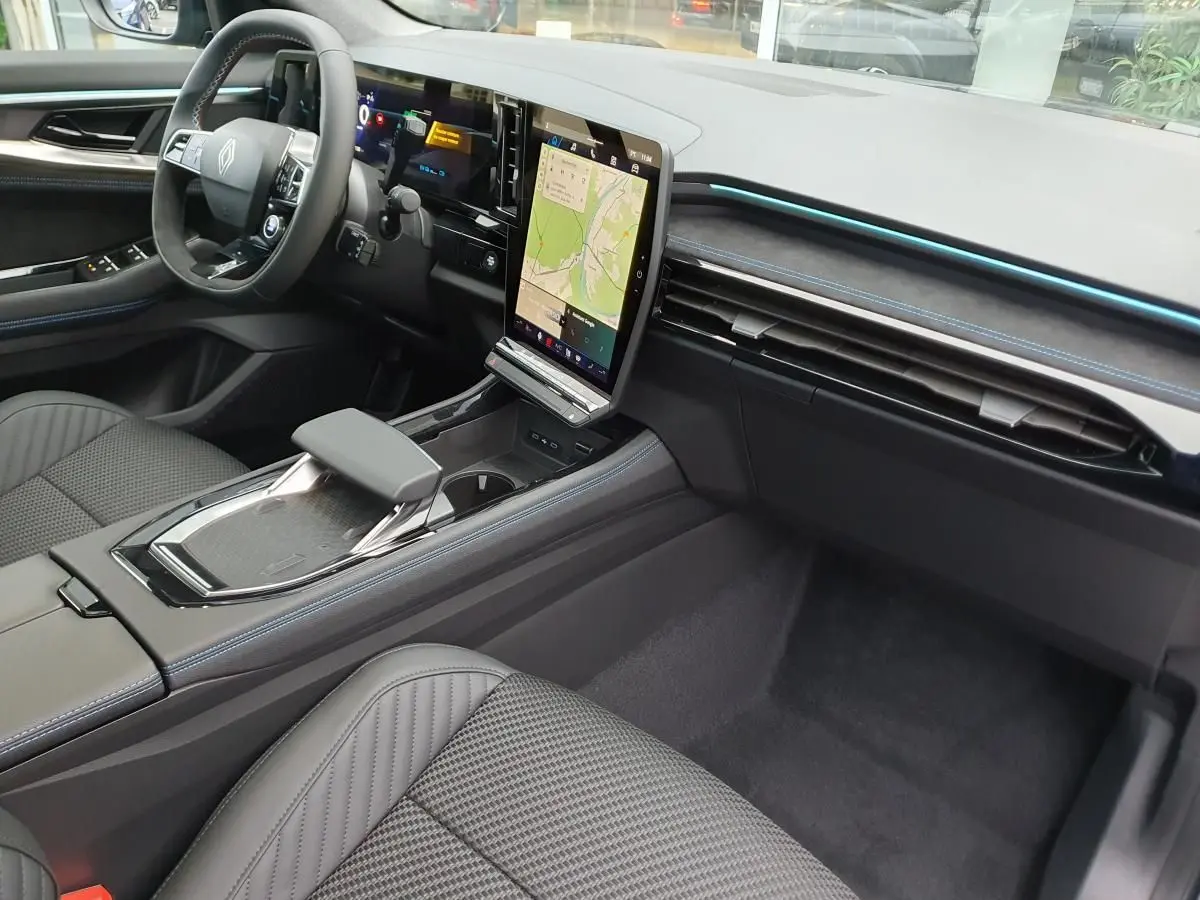 Intérieur Renault Austral 2025, vue côté conducteur, tableau de bord noir avec écran tactile vertical et surpiqûres bleues.