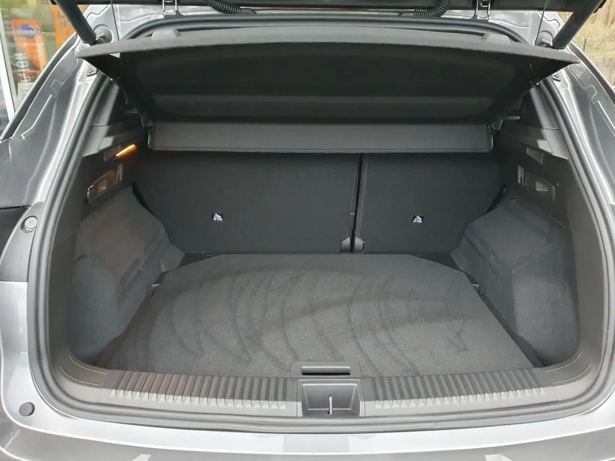 Coffre ouvert vu de l'arrière d'un Renault Austral gris schiste avec intérieur noir et cache-bagages déployé.