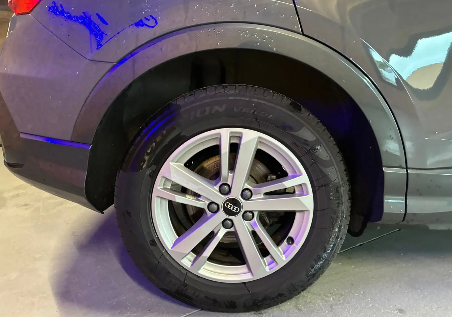 Gros plan sur la roue arrière droite avec jante aluminium 17'' argent de l'Audi Q3 Sportback gris.