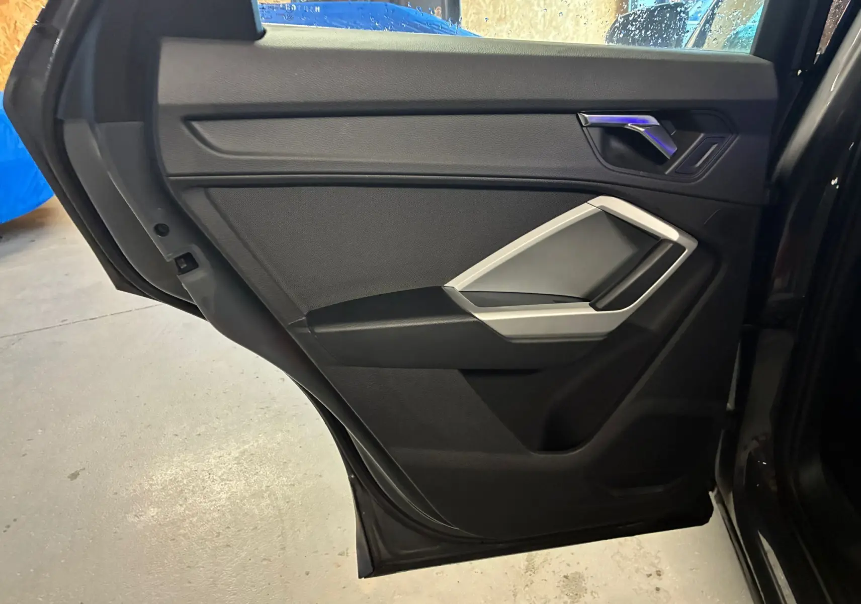 Vue intérieure de la porte arrière droite noire de l'Audi Q3 Sportback avec insert argenté et poignée chromée.