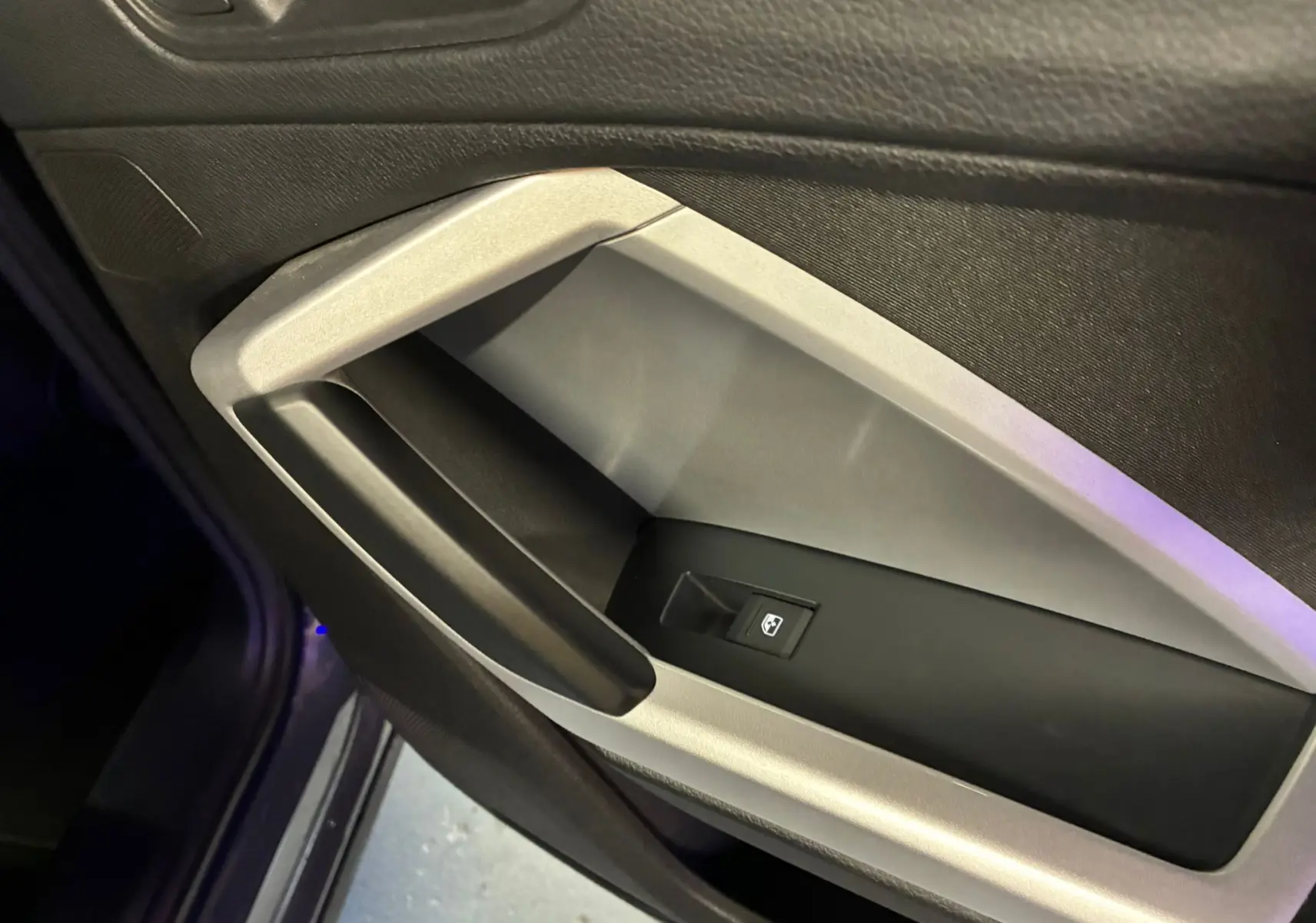 Gros plan sur la poignée intérieure côté gauche de la porte d’un Audi Q3 Sportback gris, avec insert argent micrométallique.