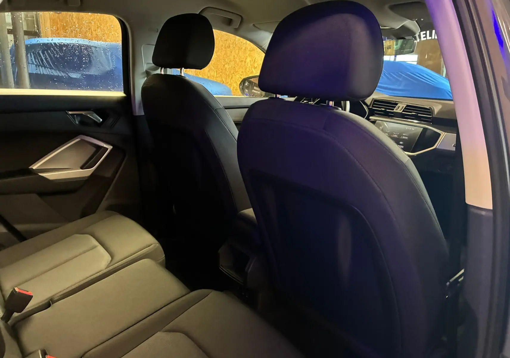 Vue intérieure arrière côté gauche de l'Audi Q3 Sportback 2021, sièges en cuir noir et tableau de bord visible.