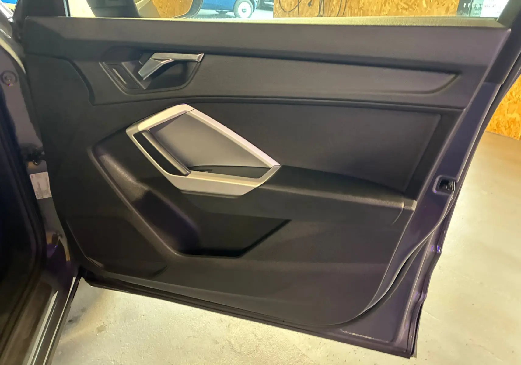 Vue intérieure de la porte arrière droite de l'Audi Q3 Sportback gris, avec poignée argentée et garniture noire.