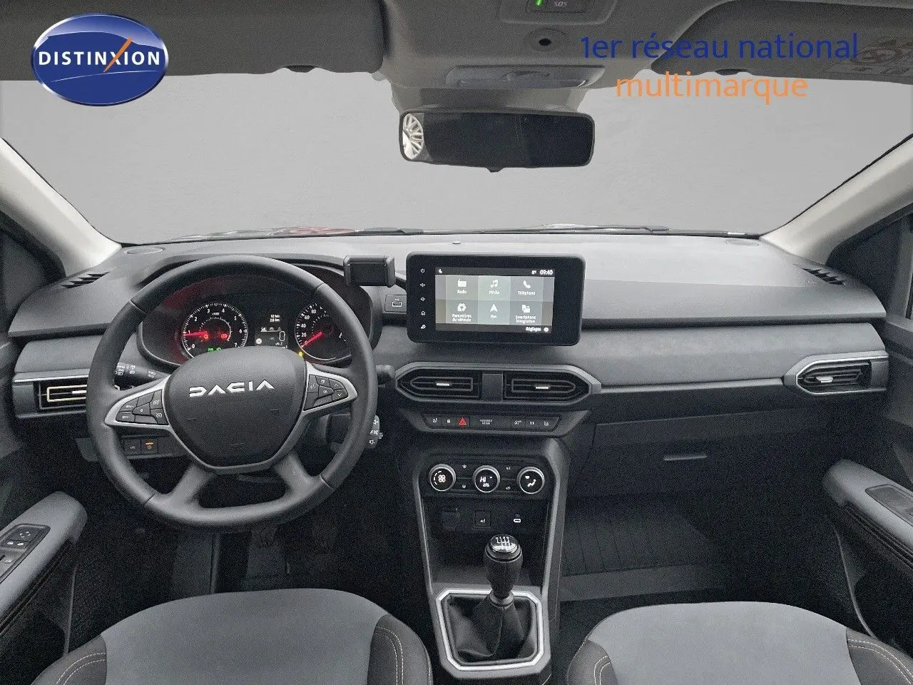 Vue intérieure avant du tableau de bord et volant noir du Dacia Jogger gris schiste métal avec écran tactile central et boîte manuelle.