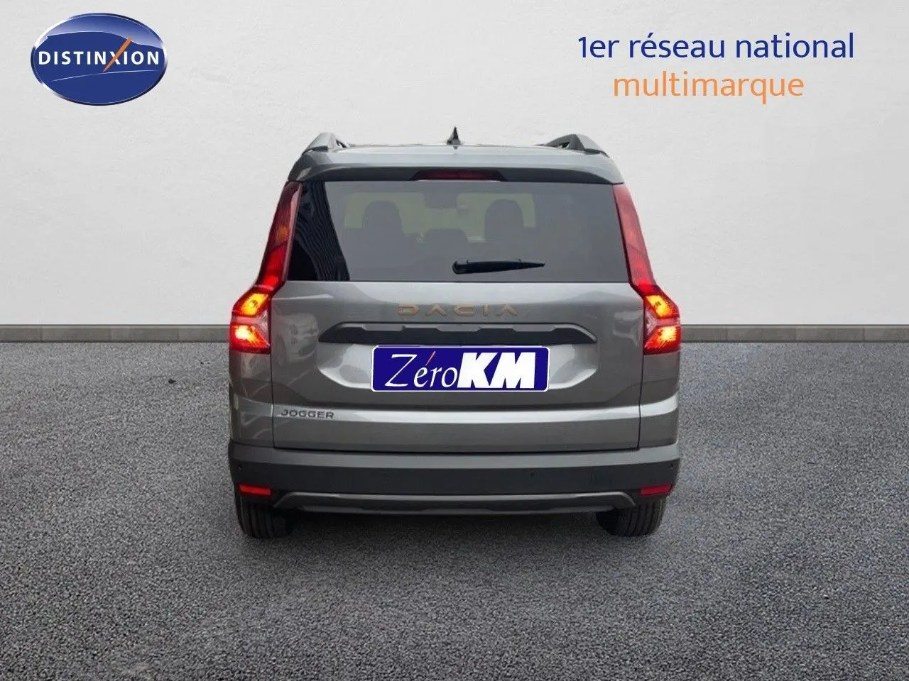 Vue arrière d'un Dacia Jogger gris schiste métal avec feux allumés sur fond neutre.