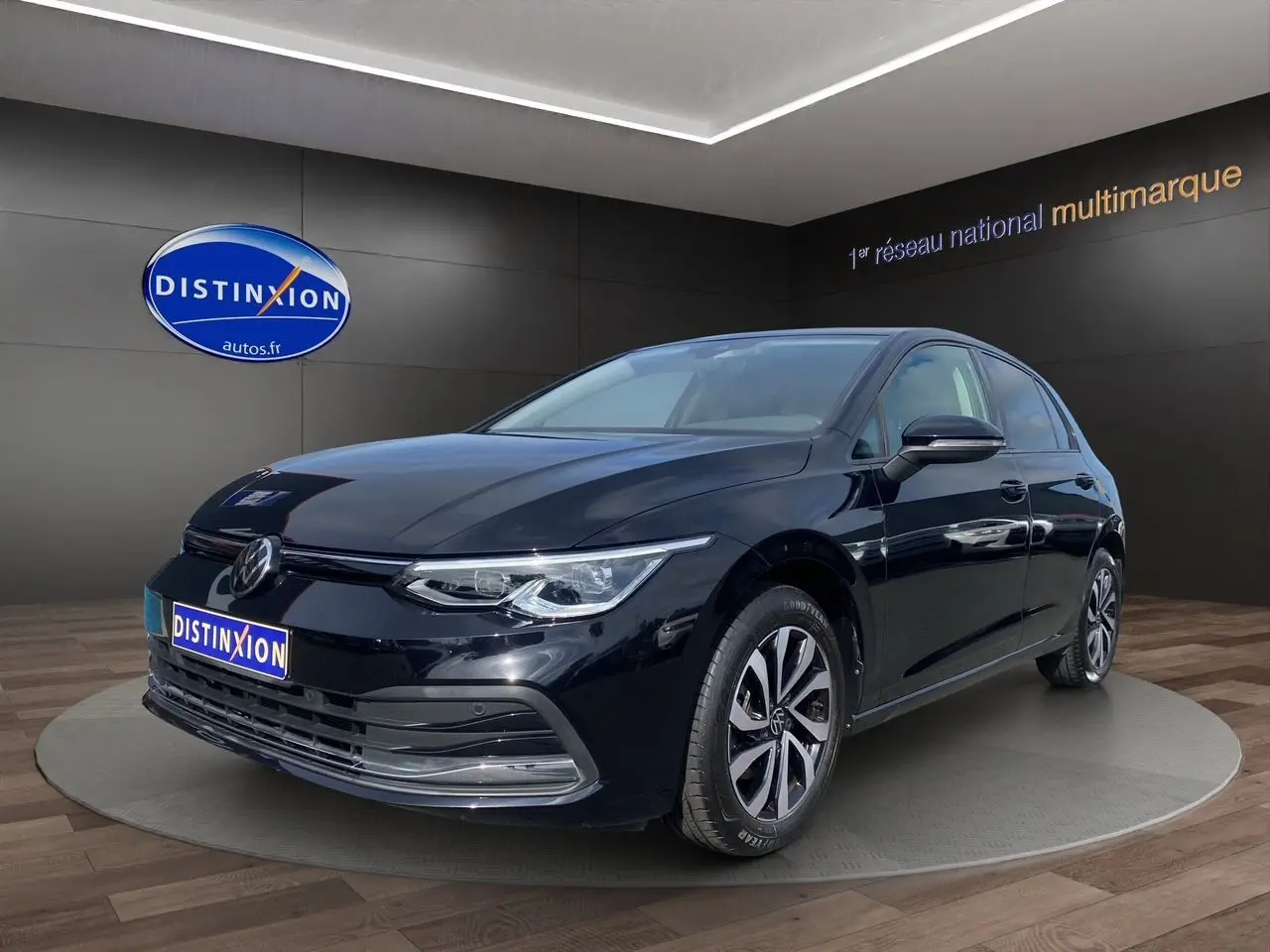 Volkswagen Golf VIII noire vue en 3/4 avant droit, avec jantes alliage et vitres surteintées dans un showroom.