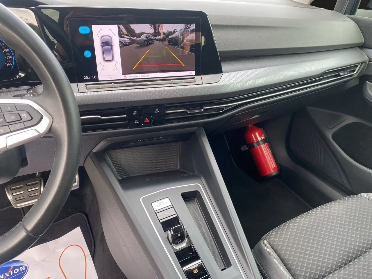 Intérieur noir de la Volkswagen Golf VIII, vue du tableau de bord et console centrale avec écran caméra de recul allumé.