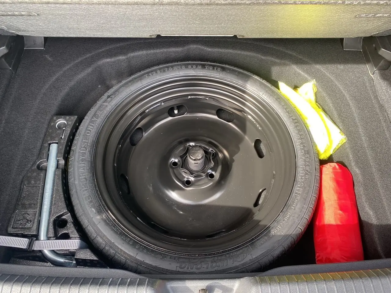 Roue de secours noire dans le coffre d'une Volkswagen Golf VIII 2022, avec outils et trousse de secours visibles.